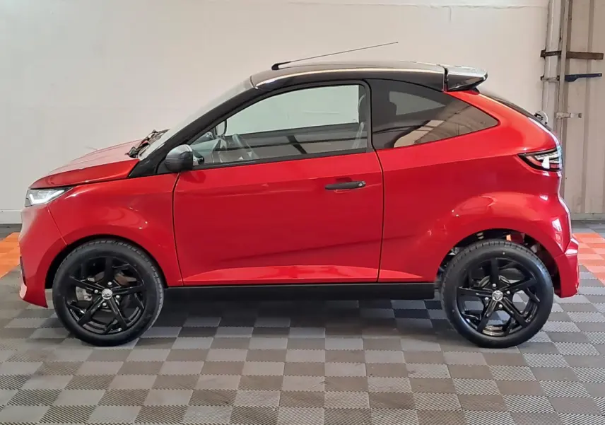 Vue de profil côté gauche d'une Aixam Ambition rouge 2025 avec jantes noires et toit noir contrasté.