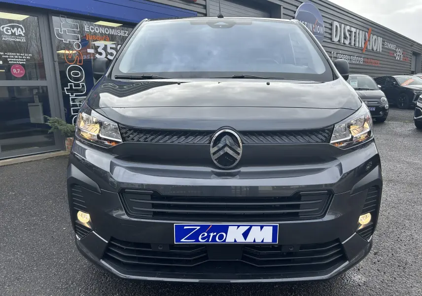 Vue de face du Citroën Jumpy Cabine Approfondie gris titane métal avec feux allumés sur parking de concession.