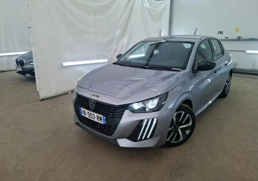 Peugeot 208 gris clair vue 3/4 avant droit dans un garage avec feux diurnes LED allumés.