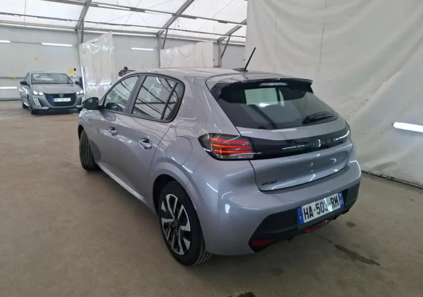 Vue 3/4 arrière droite d'une Peugeot 208 gris clair 2024, avec feux arrière LED et jantes alliage distinctives.