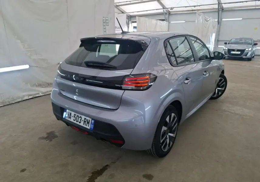 Vue 3/4 arrière droit d'une Peugeot 208 gris clair 2024 avec feux arrière LED et jantes alliage bicolores.