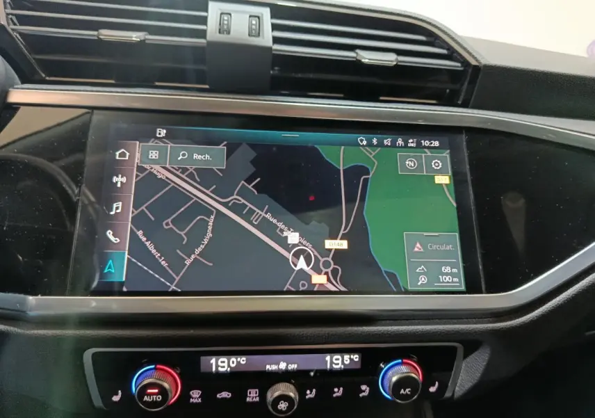 Vue rapprochée de l’écran tactile central et de la commande de climatisation du tableau de bord de l’Audi Q3 Sportback gris foncé.