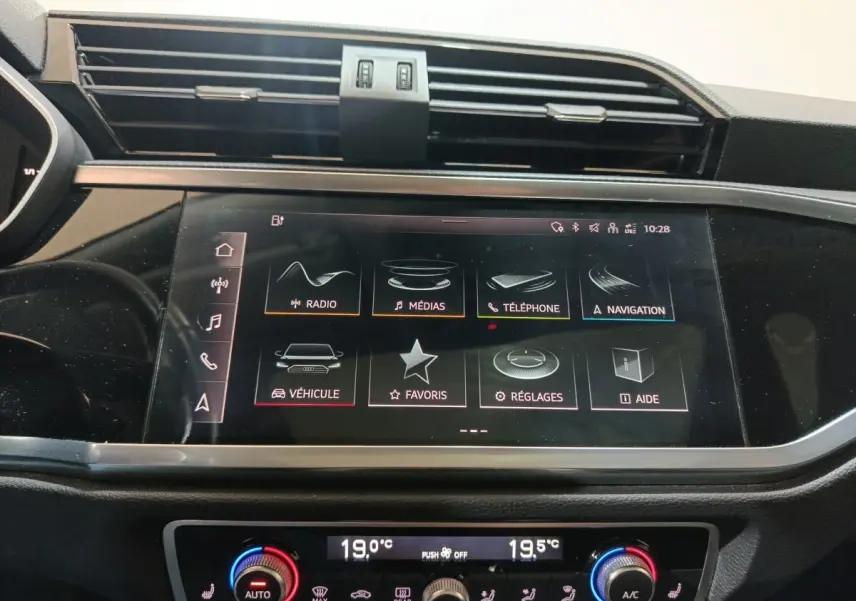 Écran tactile central de l’Audi Q3 Sportback 45 TFSI e 2021 affichant les menus multimédias et navigation, avec commandes climatisation en dessous.