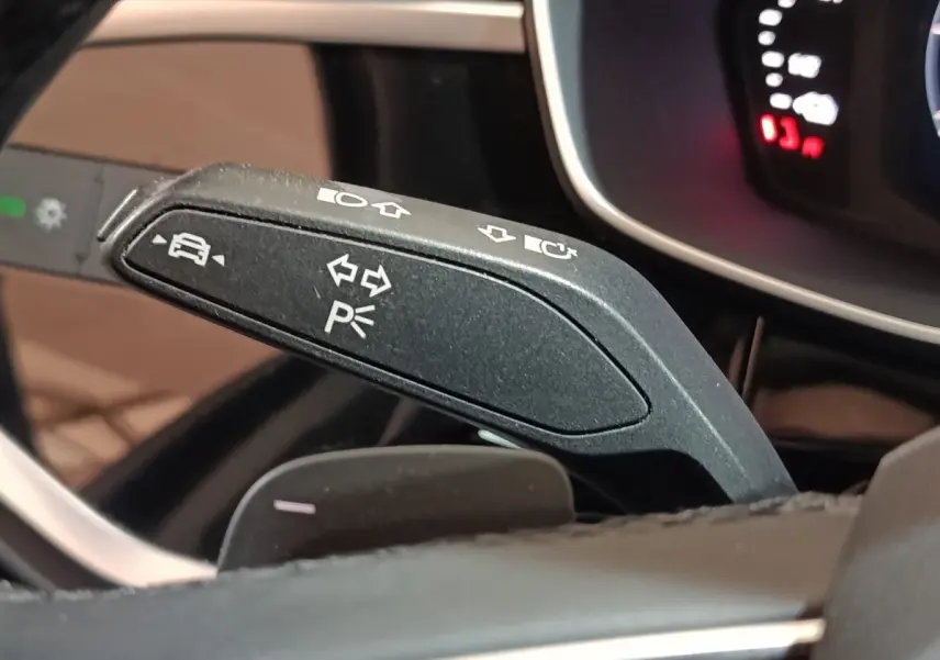 Détail du commodo de clignotant noir dans l’habitacle de l’Audi Q3 Sportback 45 TFSI e gris foncé, avec tableau de bord partiellement visible.
