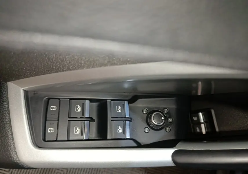 Gros plan sur les commandes des vitres électriques et rétroviseurs côté gauche de l'Audi Q3 Sportback gris foncé.
