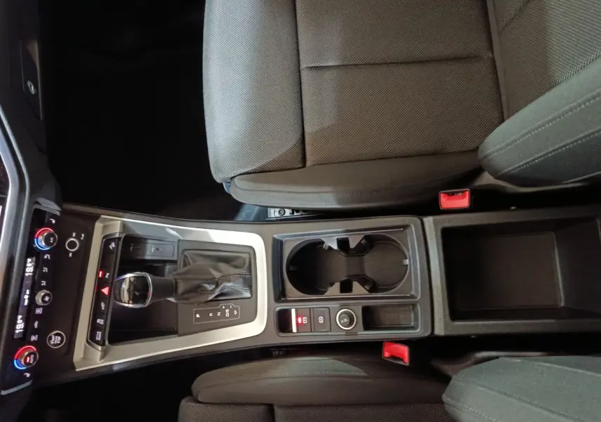 Vue plongeante sur la console centrale noire de l'Audi Q3 Sportback 45 TFSI E avec levier de vitesse et porte-gobelets.