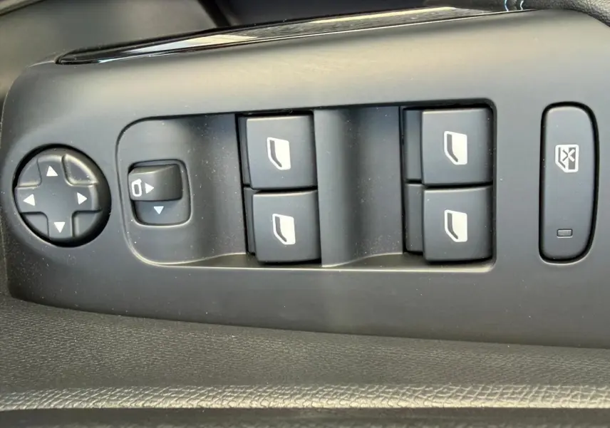 Vue rapprochée des commandes de lève-vitres et rétroviseurs sur la porte côté gauche du Citroën C5 Aircross blanc Okénite.