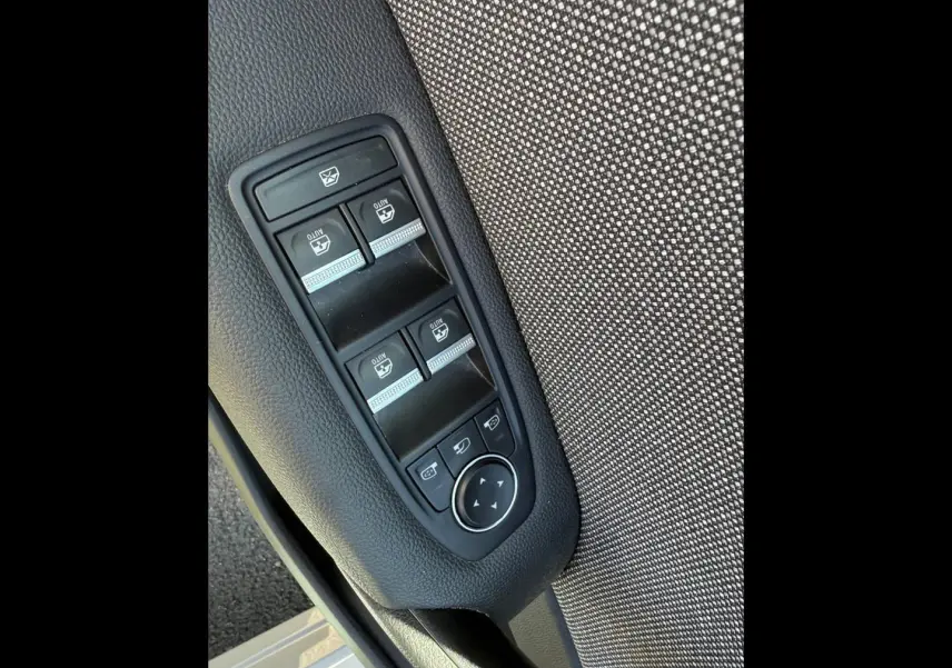 Gros plan sur les commandes des vitres électriques et rétroviseurs sur la porte avant gauche du Renault Captur gris Rafale.