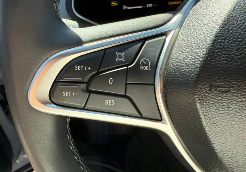 Gros plan sur les commandes de régulateur de vitesse à gauche du volant noir du Renault Captur gris Rafale 2025.