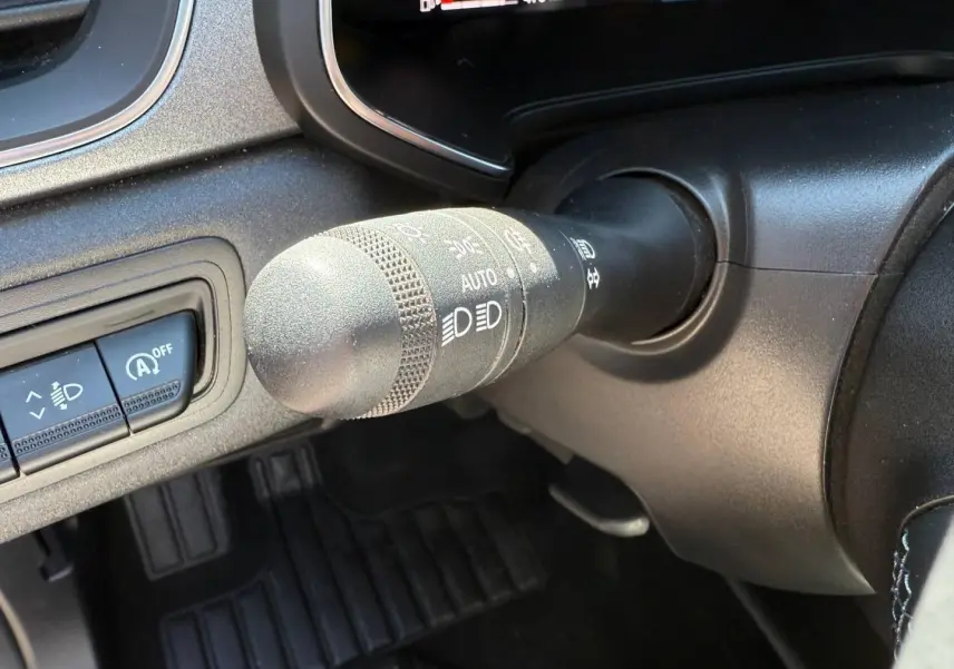 Gros plan sur la commande des phares et essuie-glaces du Renault Captur gris Rafale, tableau de bord partiel visible.