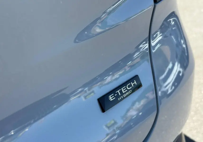 Gros plan sur l’écusson E-TECH Hybrid gris métallisé du côté gauche arrière du Renault Captur 2025.