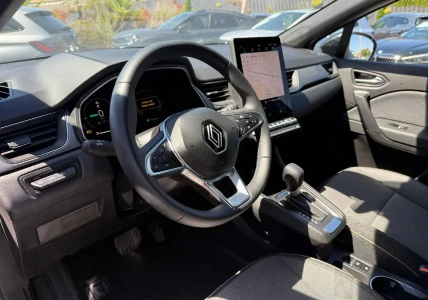 Intérieur Renault Captur 2025 vu côté conducteur, volant multifonction et écran tactile vertical en évidence.