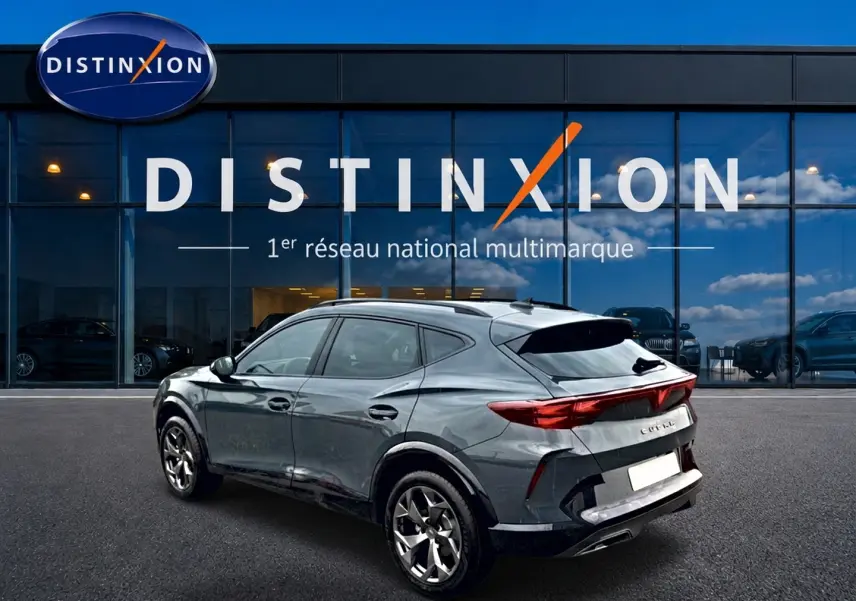 Vue 3/4 arrière droite d'un CUPRA Formentor gris métallisé stationné devant une vitrine Distinxion.
