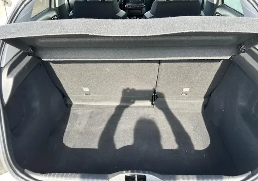 Coffre ouvert vu de l'arrière d'une Citroën C3 sable métal 2021, intérieur gris avec banquette rabattable.