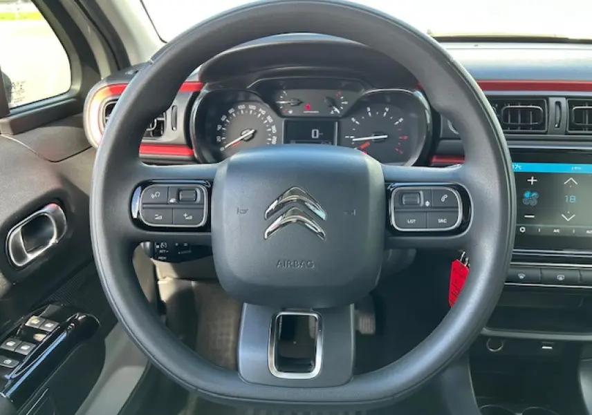 Vue centrée sur le volant noir de la Citroën C3 1.2 PureTech 83 avec tableau de bord et écran tactile rouge sable.