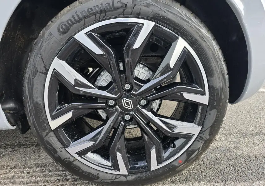 Gros plan sur la jante alliage 17 pouces noir et argent de la Renault Clio V Gris Rafale, avec logo Renault central.