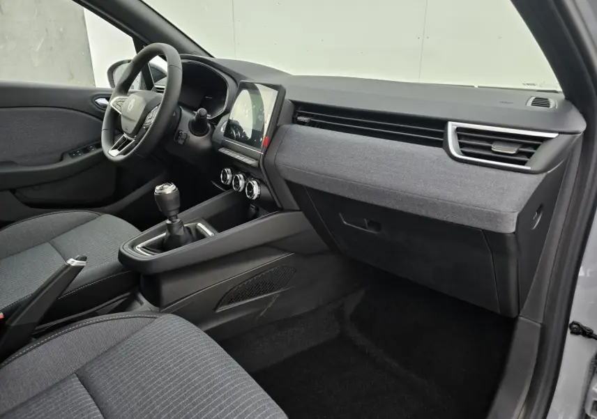 Intérieur avant droit de la Renault Clio V 2025 gris Rafale, avec tableau de bord tissu gris et boîte manuelle.
