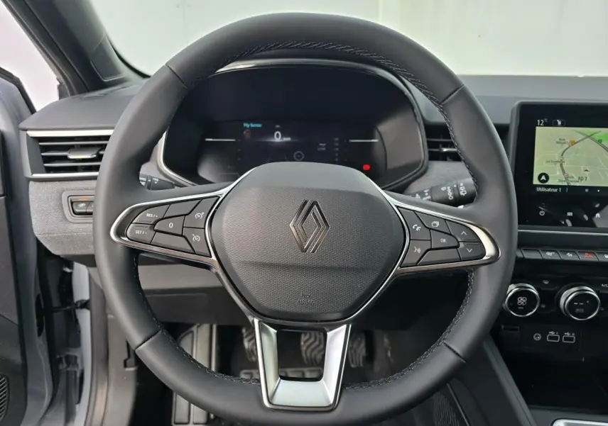 Vue centrée sur le volant multifonction noir de la Renault Clio 2025 avec tableau de bord numérique et écran tactile.