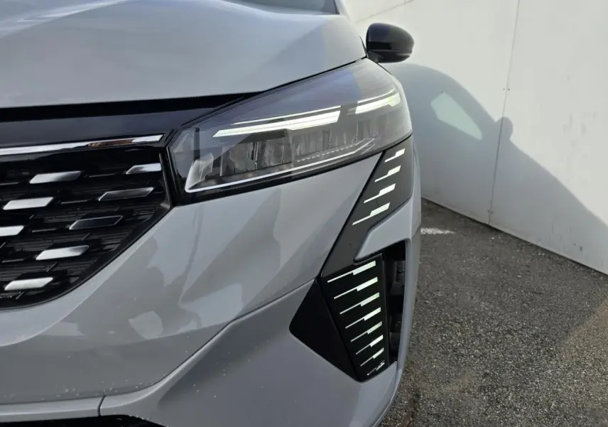 Gros plan sur l'avant droit de la Renault Clio 2025 gris Rafale Métal avec phares LED et calandre noire chromée.