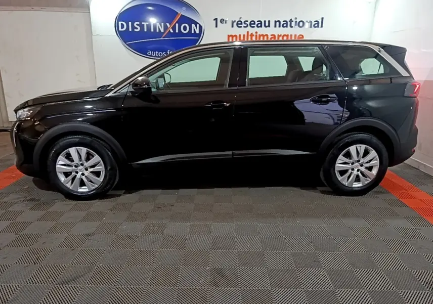 Peugeot 5008 noir vue de profil côté gauche dans un showroom avec jantes alliage et vitres teintées.