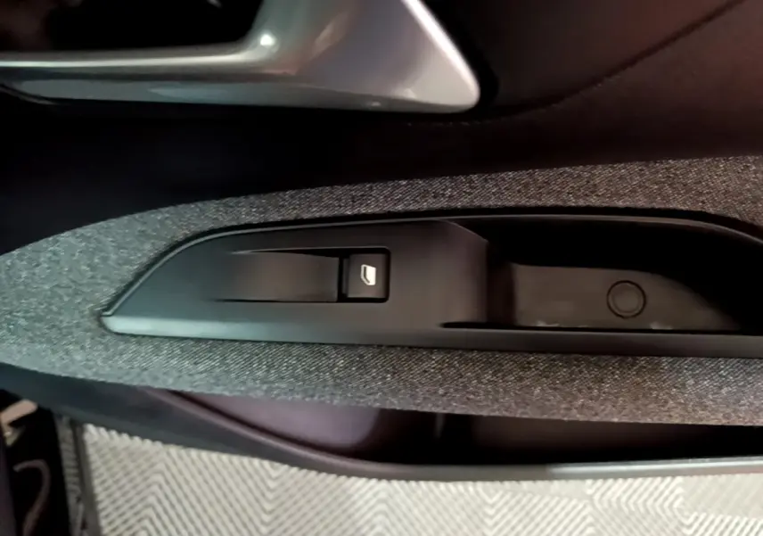 Gros plan sur la commande de lève-vitre côté conducteur du Peugeot 5008 noir, avec insert tissu gris foncé.