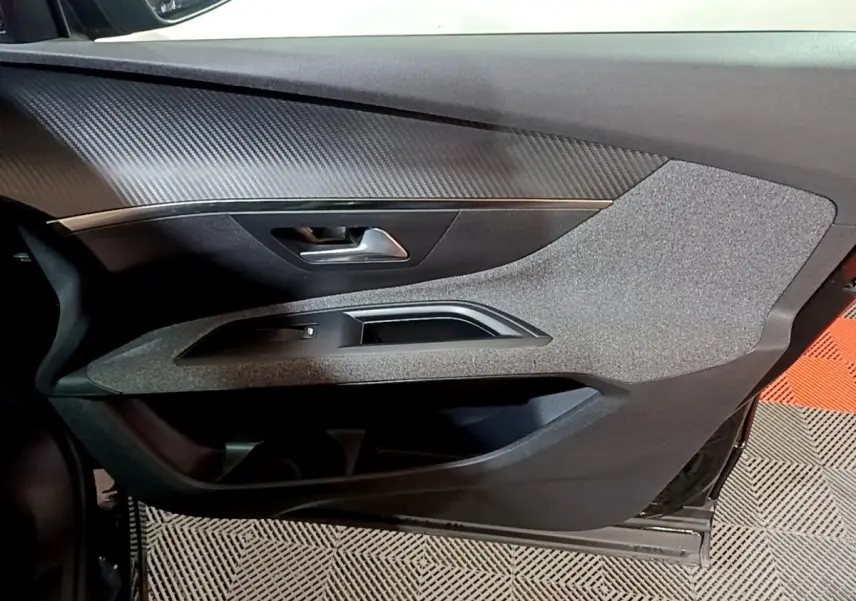Vue rapprochée de la porte intérieure côté conducteur du Peugeot 5008 noir, avec garniture texturée et poignée métallique.
