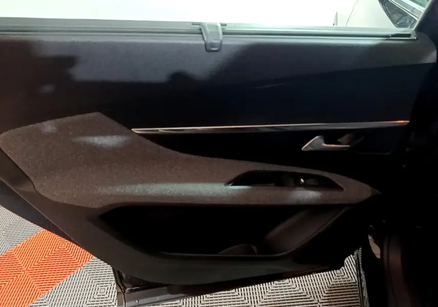 Vue intérieure du panneau de porte côté gauche du Peugeot 5008 noir, avec poignée argentée et commande de vitre intégrée.