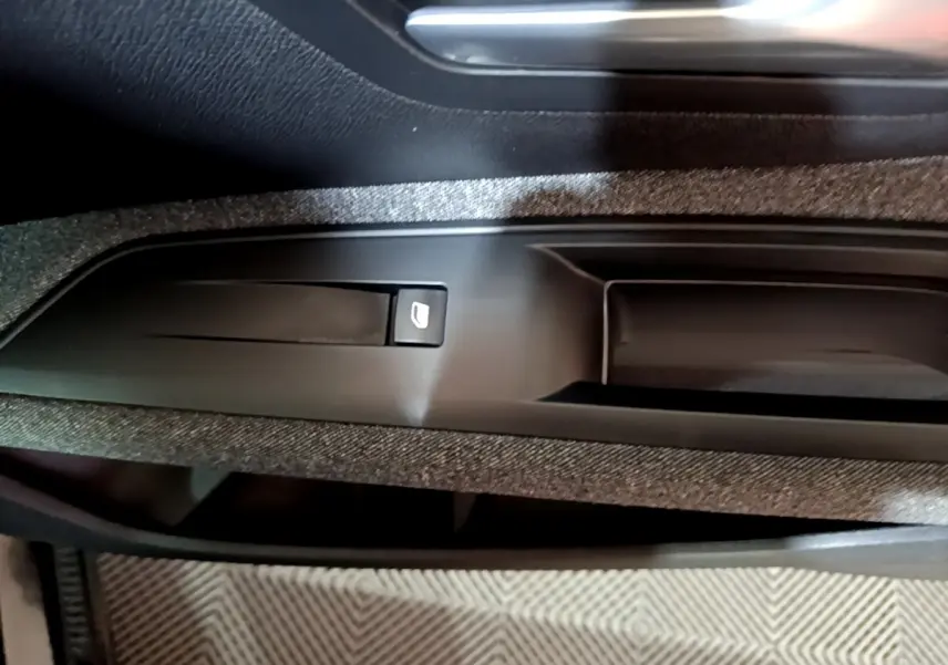 Gros plan sur la commande de lève-vitre électrique intégrée dans la garniture de porte intérieure noire du Peugeot 5008.