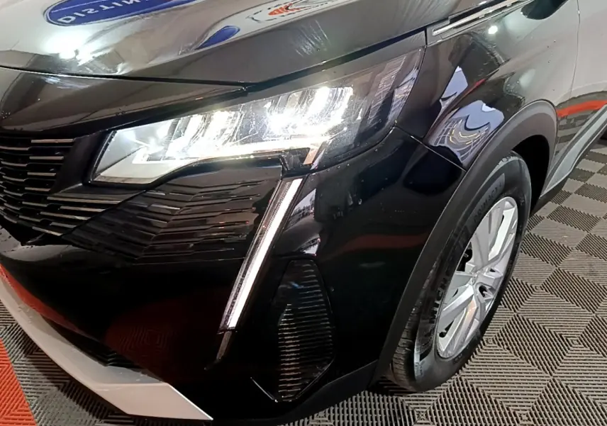 Gros plan sur l'avant droit noir du Peugeot 5008 2021 avec phares LED allumés et jante argentée visible.