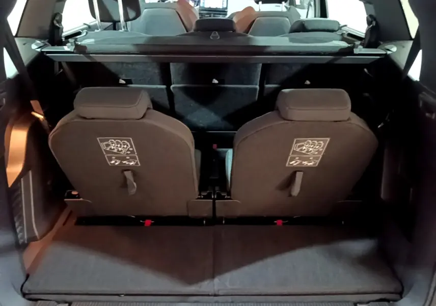Vue arrière du coffre ouvert du Peugeot 5008 noir, montrant la troisième rangée de sièges individuels rabattus.