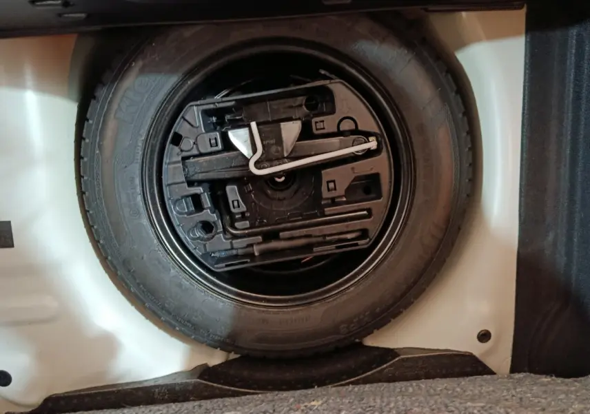 Vue rapprochée de la roue de secours noire dans le coffre blanc d'une Citroën C3 PureTech 2020.