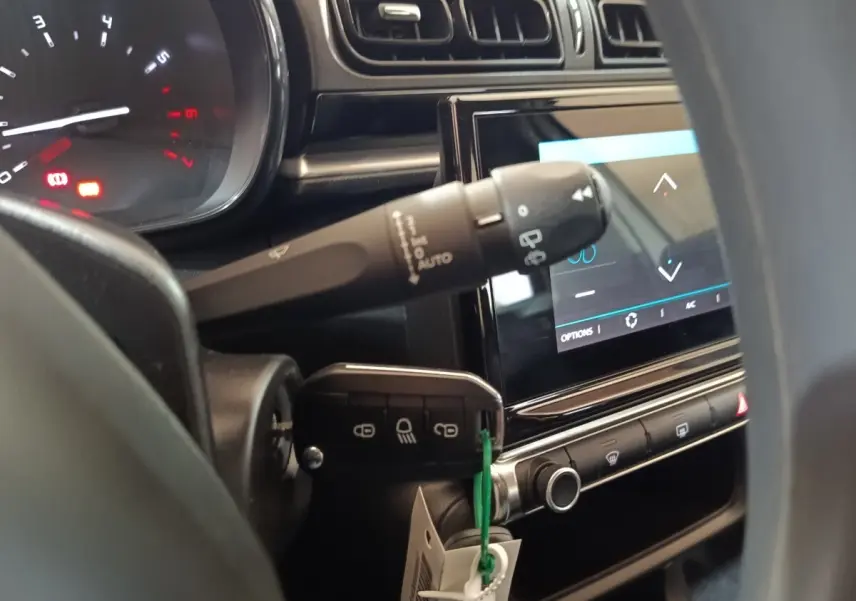Gros plan intérieur sur le tableau de bord et la clé insérée d'une Citroën C3 blanche, avec écran tactile allumé.