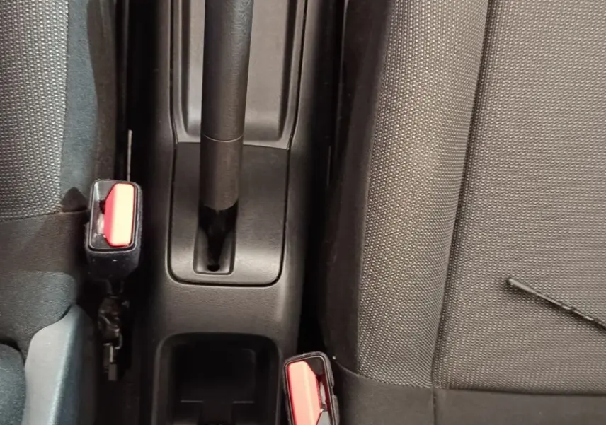 Vue plongeante sur la console centrale noire de la Citroën C3 avec frein à main manuel et sièges tissu gris foncé.
