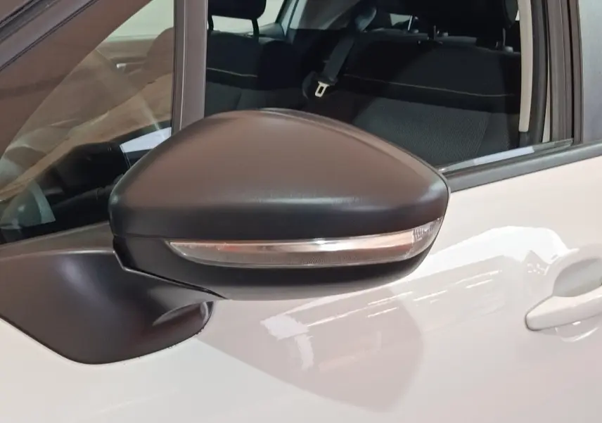 Rétroviseur noir avec clignotant intégré sur porte avant gauche d'une Citroën C3 blanche vue de près.
