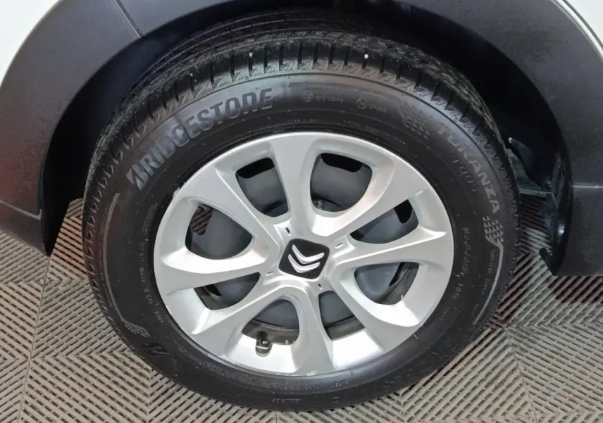 Gros plan sur la roue avant droite d'une Citroën C3 blanche avec jante alliage et logo Citroën central.