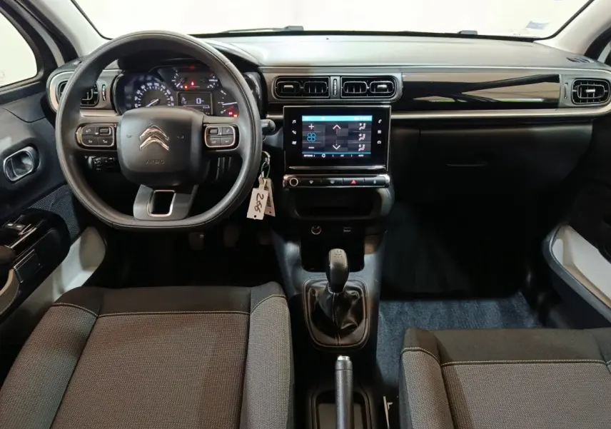 Vue intérieure avant de la Citroën C3 blanche, mettant en valeur le volant multifonctions, la boîte manuelle et l’écran tactile central.