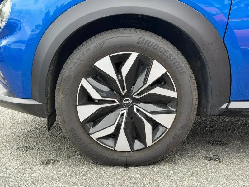 Gros plan sur la roue avant gauche du Nissan Juke 2025 bleu magnétique avec jante noire et argentée au design moderne.