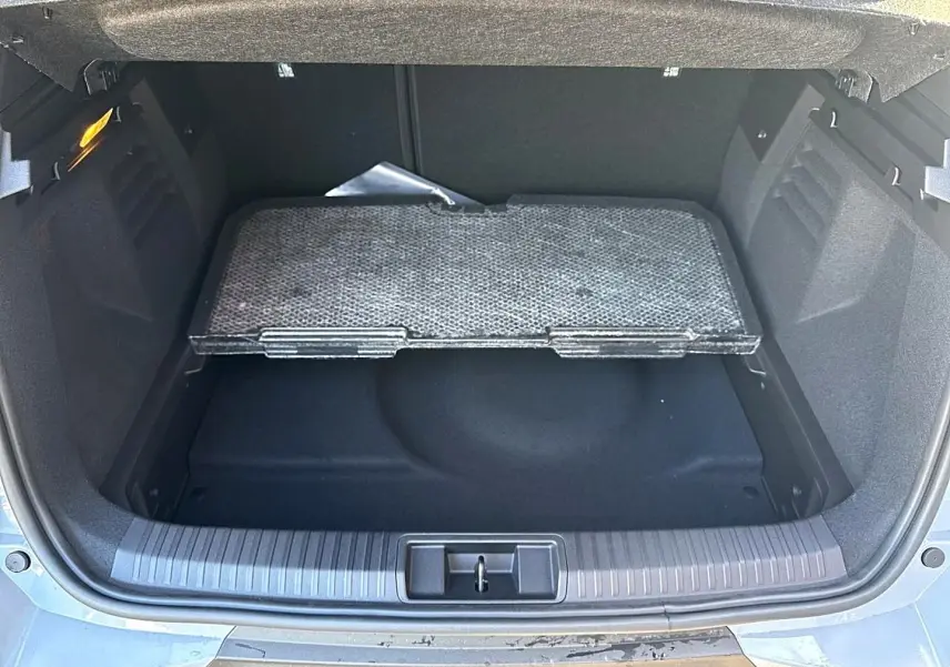 Coffre ouvert d’une Renault Symbioz gris rafale, montrant le plancher de coffre mobile et l’espace de rangement.