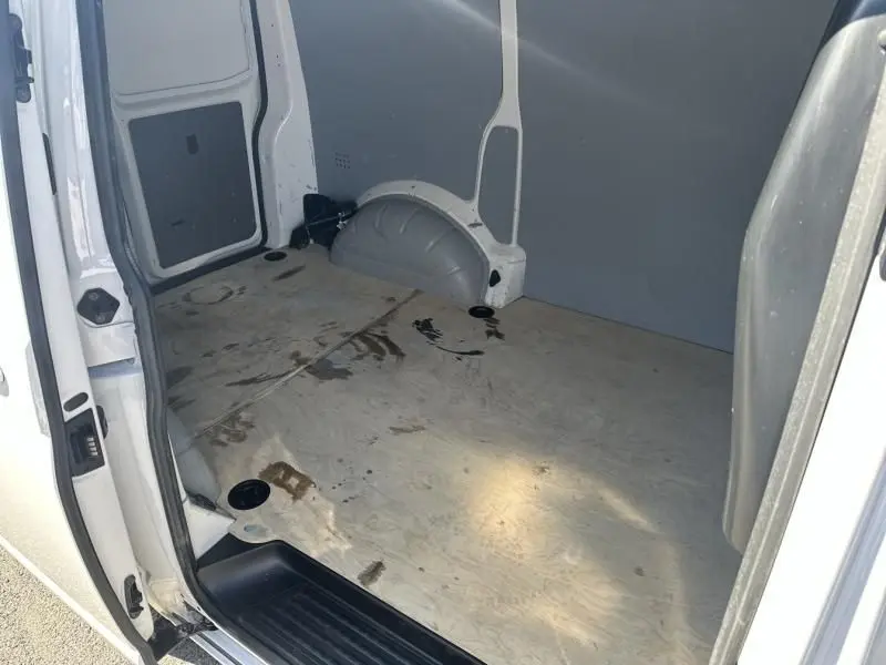 Intérieur du coffre du Volkswagen Transporter blanc 2022, vue depuis la porte latérale ouverte, plancher en bois marqué.