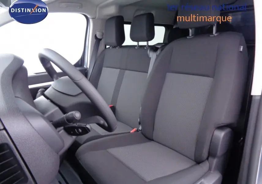 Vue intérieure côté conducteur du Peugeot Expert Long 2023, sièges noirs en tissu et volant visible.