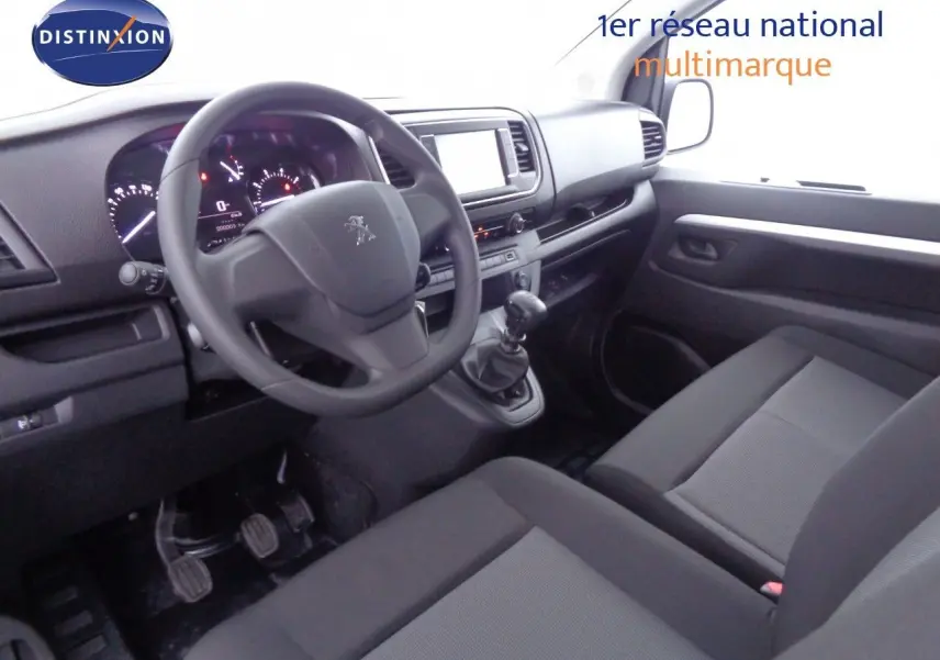 Intérieur du Peugeot Expert Long 2023 vu côté conducteur, avec tableau de bord moderne et sièges noirs en tissu.