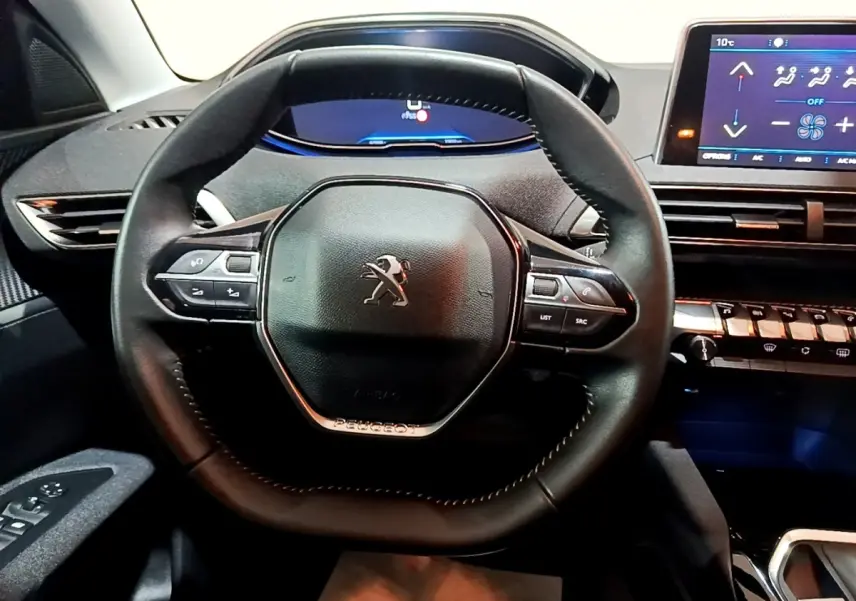 Vue rapprochée du volant cuir noir du Peugeot 3008 avec tableau de bord digital et écran tactile à droite.