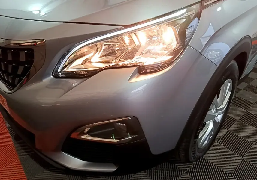Gros plan sur l'avant droit gris clair du Peugeot 3008 avec phare allumé et jante visible.