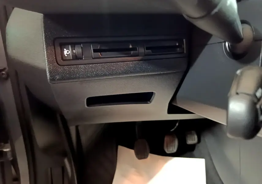 Vue intérieure en gros plan du tableau de bord côté gauche avec commandes d'éclairage et pédales d'une Peugeot 3008 gris clair.