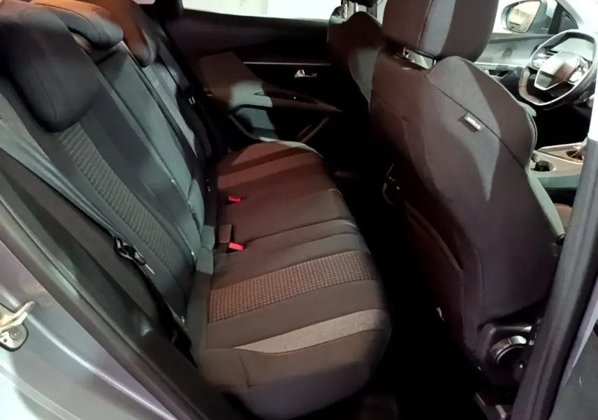 Vue intérieure côté gauche des sièges arrière noirs du Peugeot 3008 gris clair, avec partie avant et volant visibles.