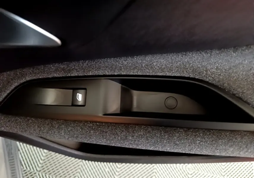 Bouton de commande de lève-vitre électrique sur la porte intérieure côté conducteur du Peugeot 3008 gris clair.