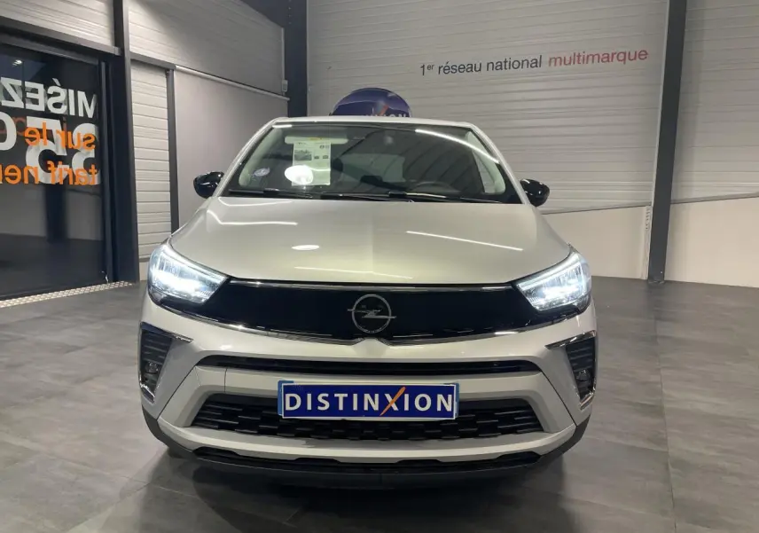 Vue frontale d'un Opel Crossland gris clair 2024 avec phares LED allumés dans un showroom.