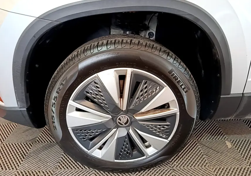 Gros plan sur la roue avant gauche d’un Skoda Karoq gris clair avec jante alliage au design moderne.