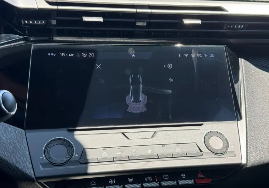 Vue rapprochée de l’écran tactile central et commandes grises du tableau de bord de la Peugeot e-308 noire.