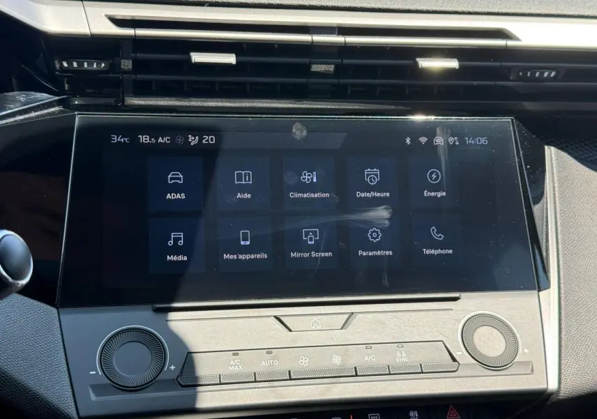 Écran tactile central de la Peugeot e-308 2025 en vue frontale, avec commandes climatisation et interface digitale.
